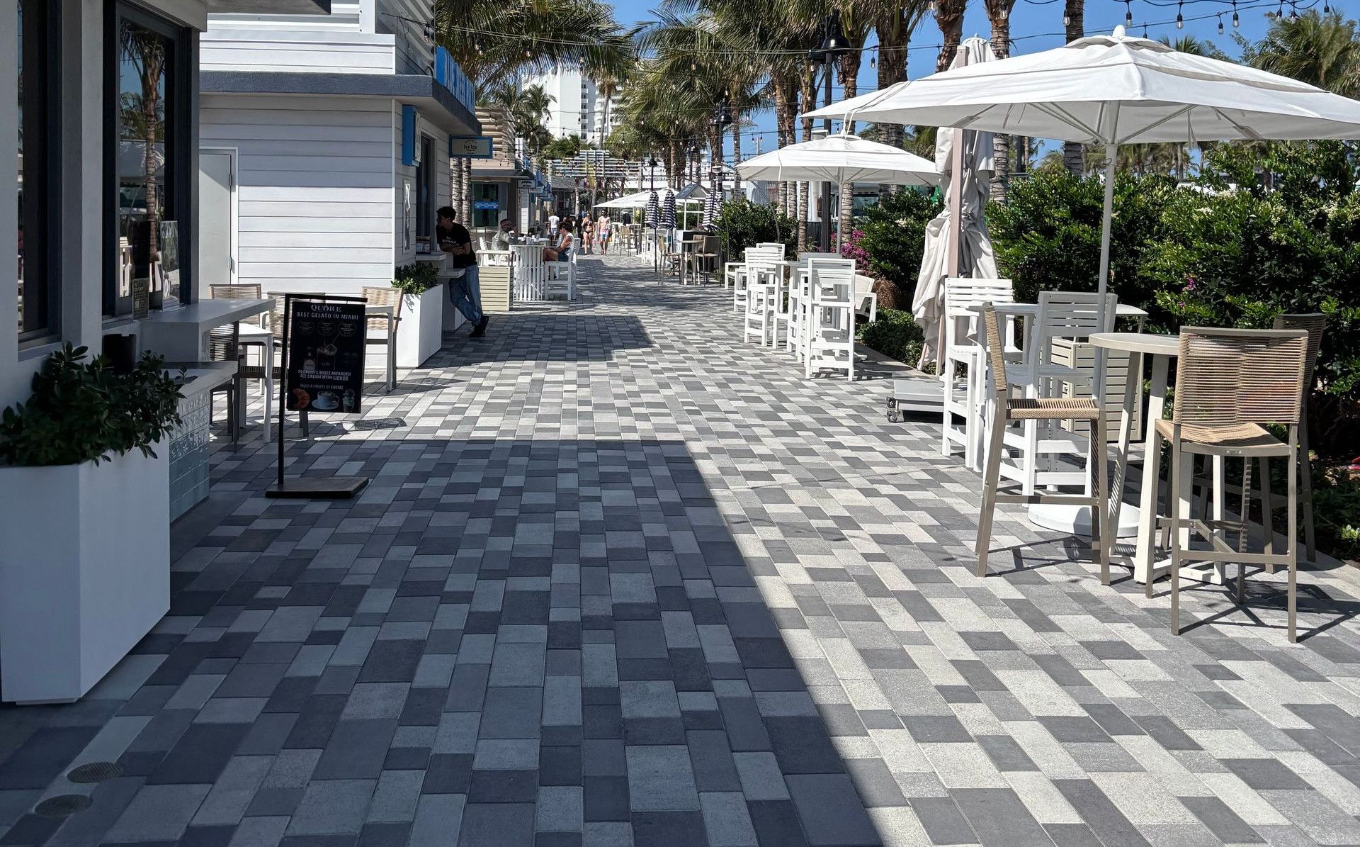 Explore a vibrant beachfront promenade in Fort Lauderdale with palm trees and outdoor seating.